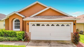 A residential house with a garage, a driveway, and a well-maintained lawn. - 4BR Villa Near Disney w/ Game Room & Private Pool (Kissimmee)