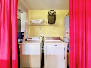 A laundry room with two washing machines, a drying rack, and a shelf with a bag. - 4BR Villa Near Disney w/ Game Room & Private Pool (Kissimmee)