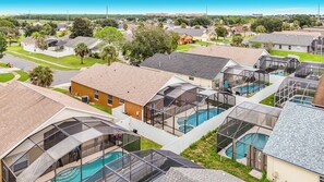 A residential area with multiple houses, some with large glass-enclosed swimming pools. - 4BR Villa Near Disney w/ Game Room & Private Pool (Kissimmee)
