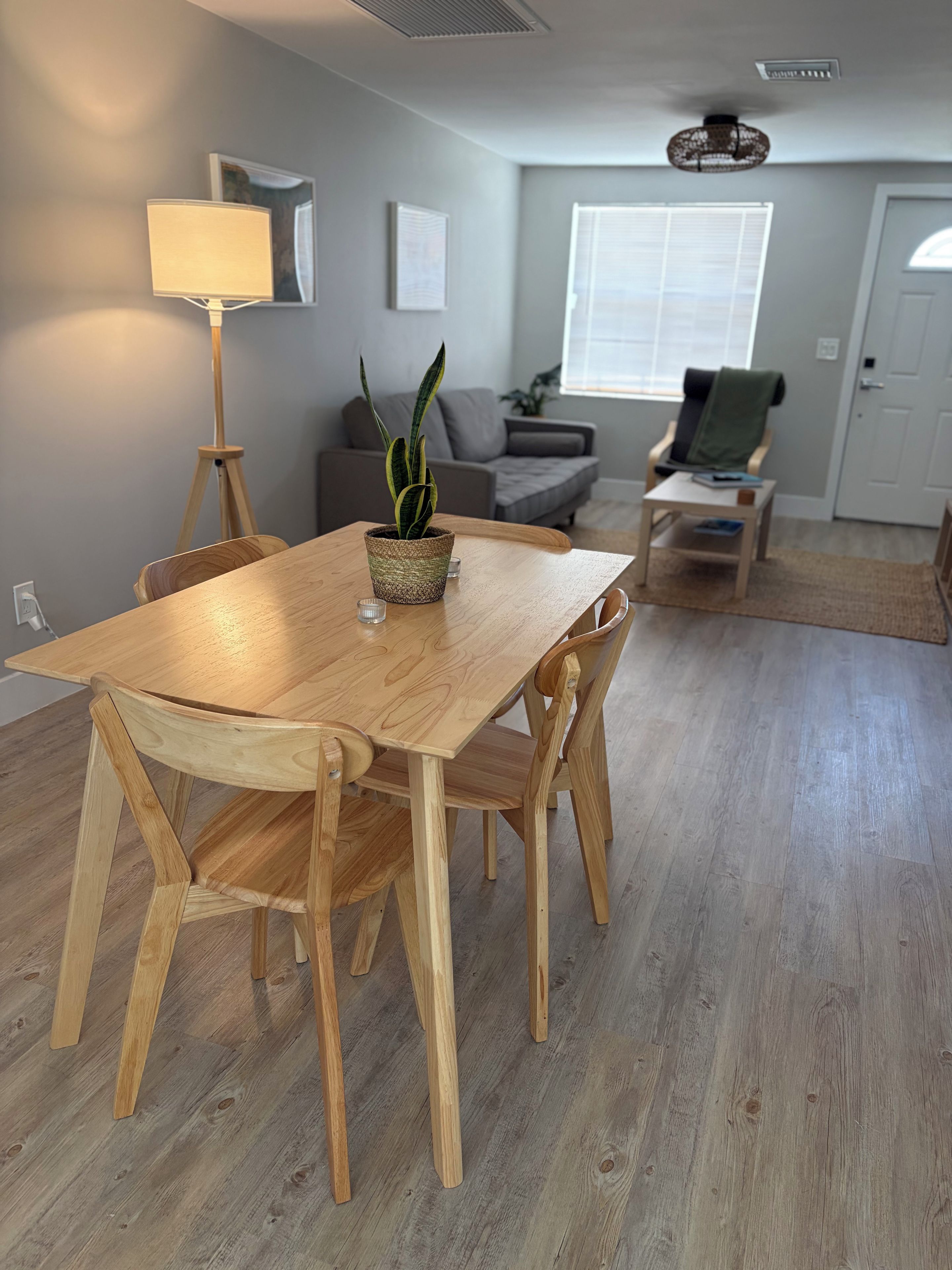 Ein Essbereich mit Holztisch und Stühlen, einer Topfpflanze und einer Lampe.
