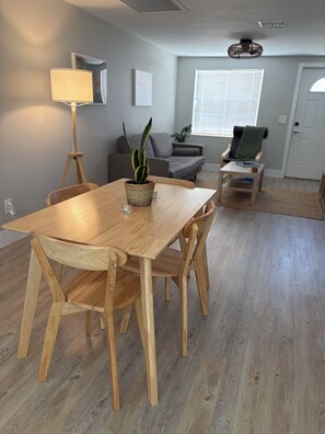 Un coin repas avec une table et des chaises en bois, une plante en pot et une lampe.