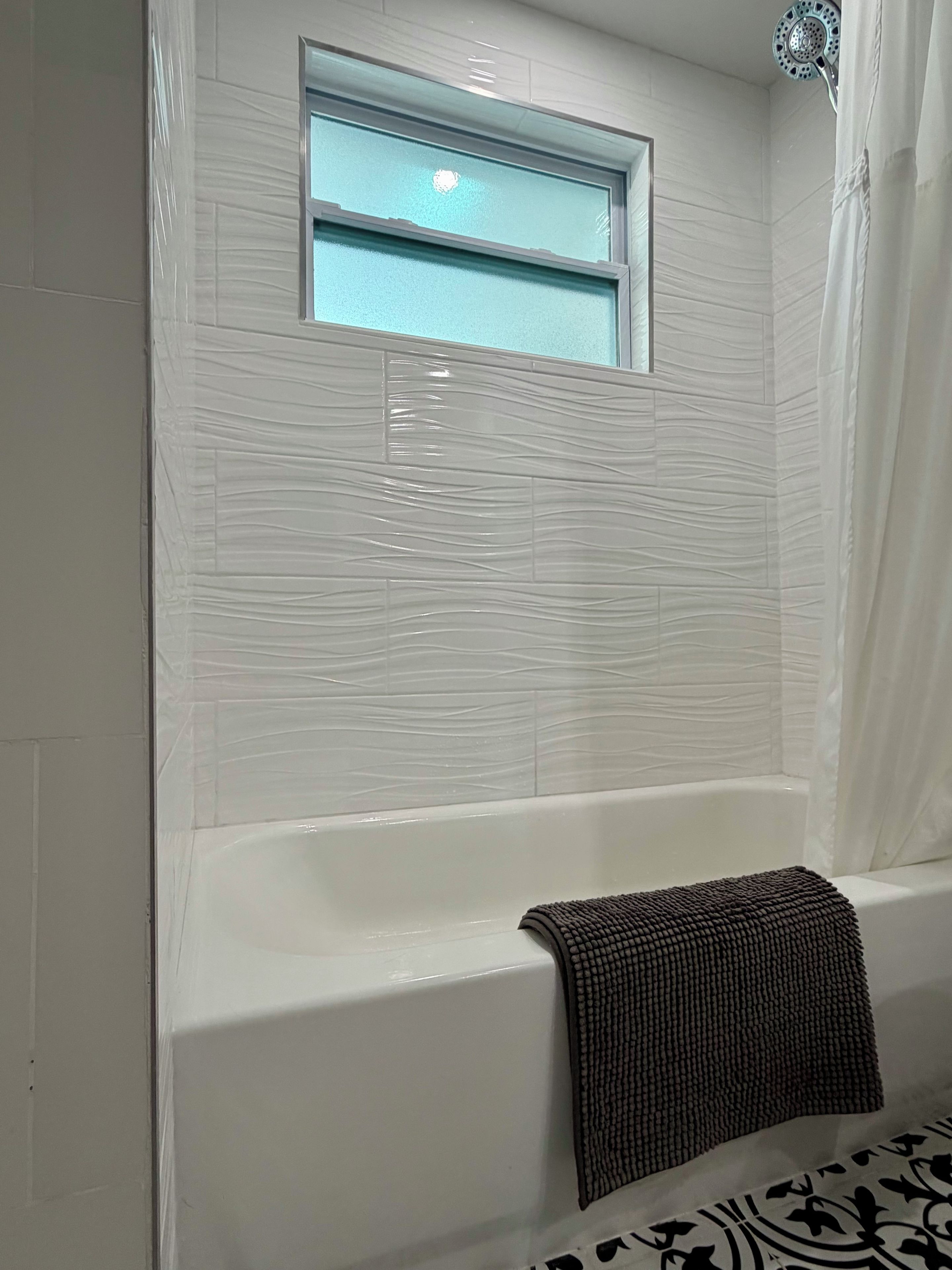 Ein Badezimmer mit einer Badewanne, einem Fenster und einer Duschvorhang.