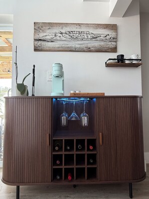 A wooden cabinet with a wine rack, a coffee machine, and a decorative wall piece.