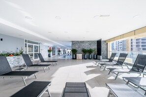 A modern indoor pool area with lounge chairs, a pool, and a view of a building under construction. - Chic 1BR Retreat High Floor Dubai Marina (Dubai)