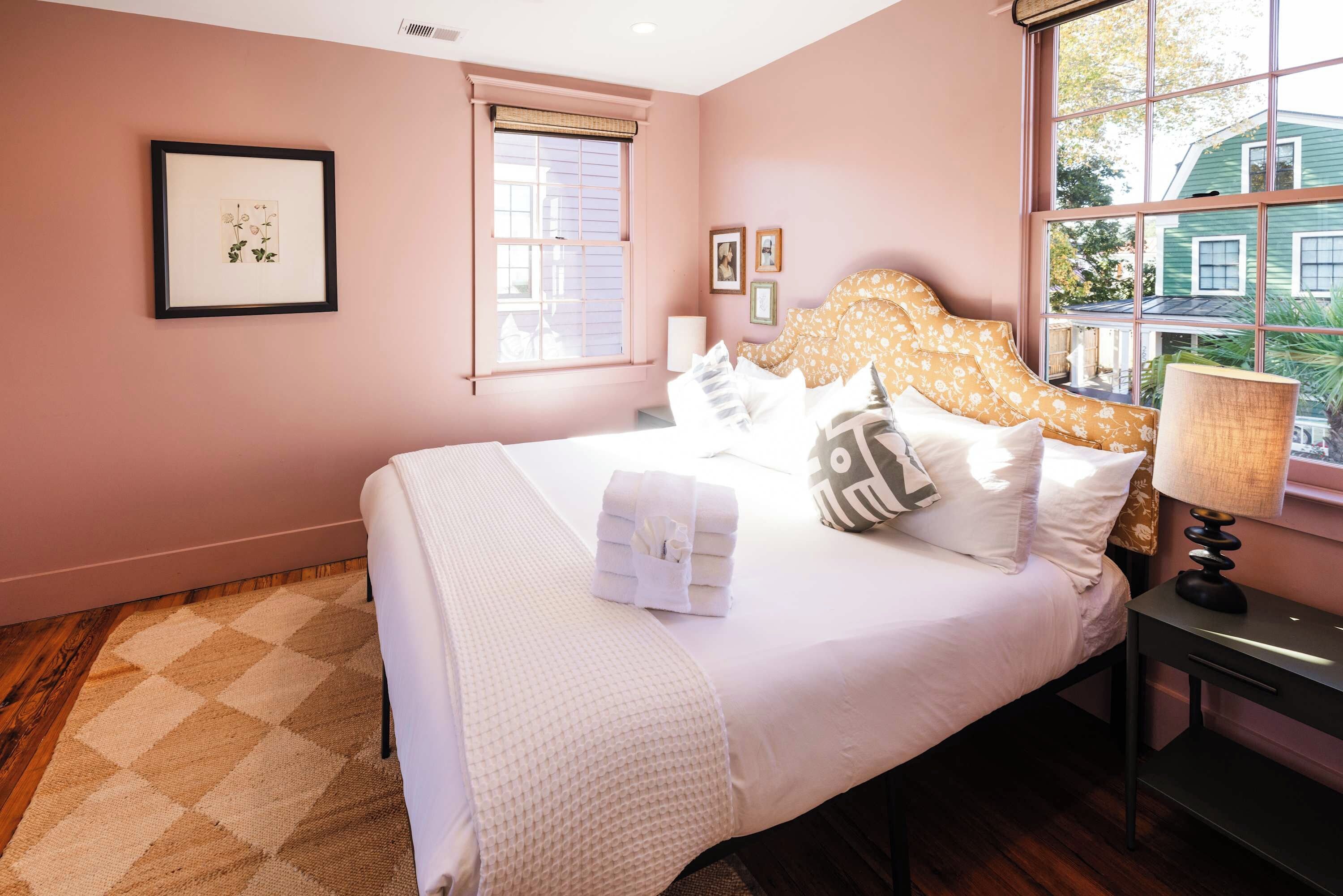 A bedroom with a bed, a nightstand, a window, and a door.
