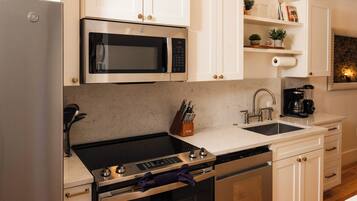 A modern kitchen with a stainless steel refrigerator, a built-in microwave, a gas stove, a dishwasher, and a sink.