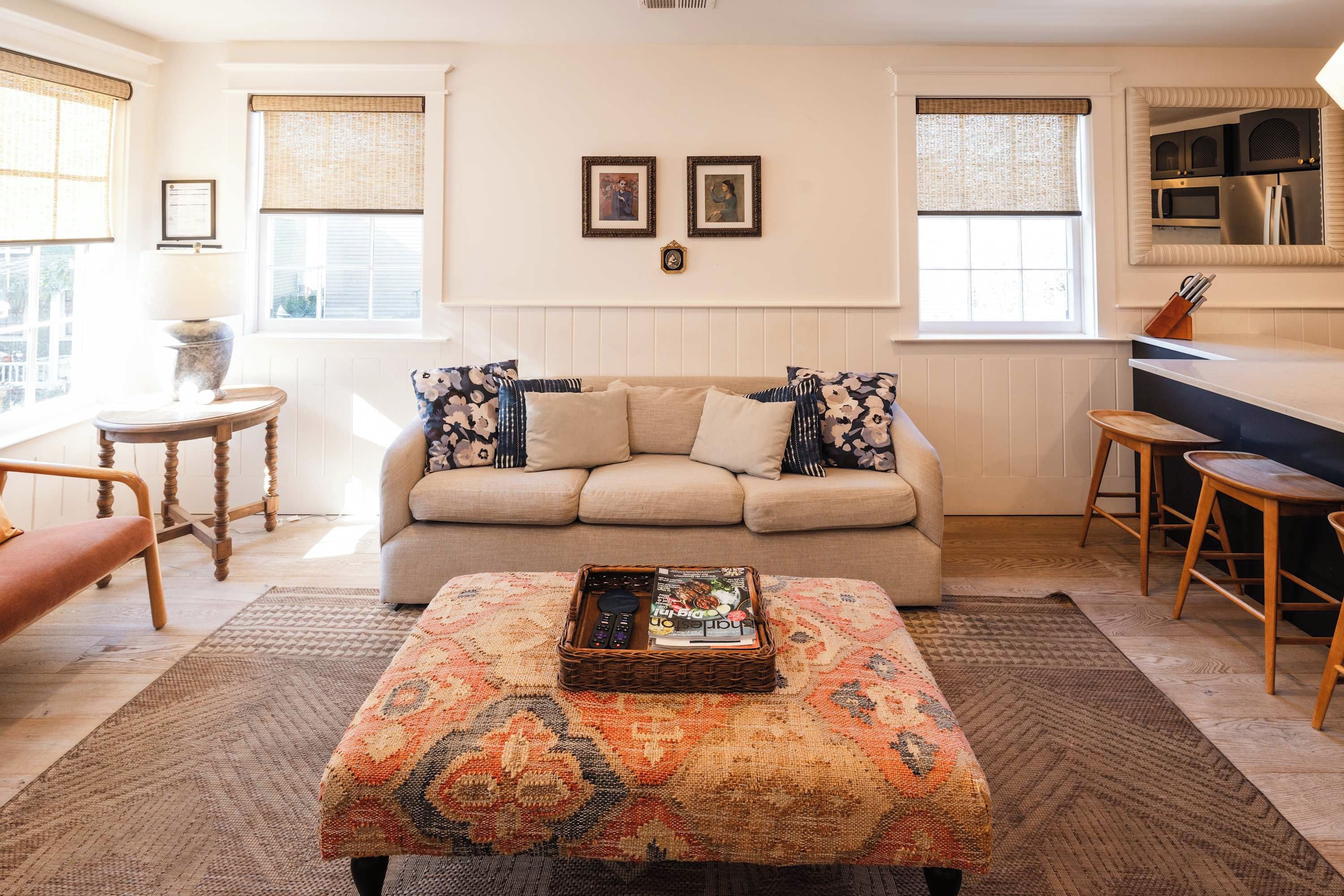 A living room with a sofa, a coffee table, a side table, and a kitchen area with a counter and stools.