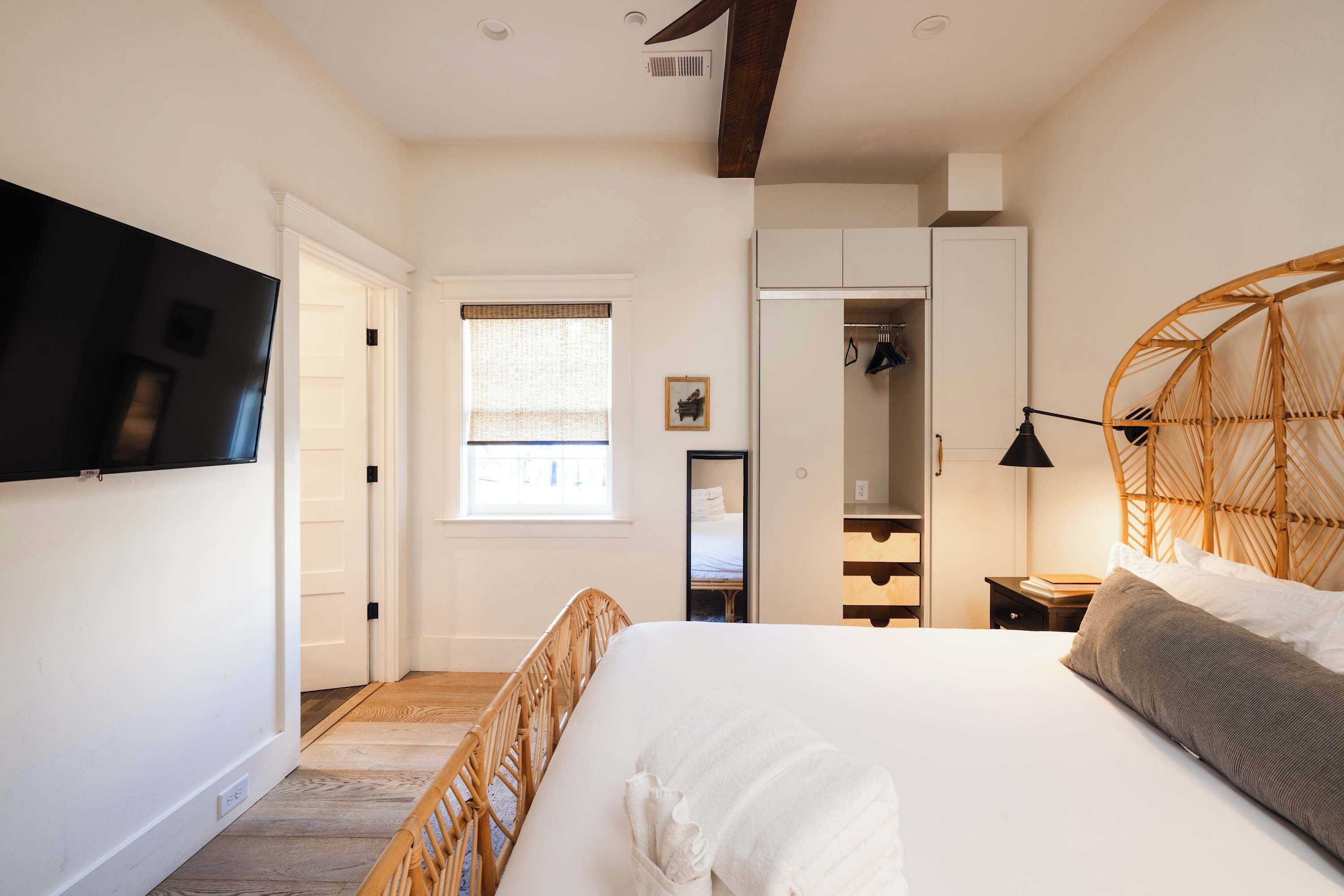 A bedroom with a bed, a wardrobe, a television, and a window.