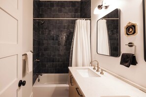 A bathroom with a bathtub, a sink, a mirror, and a shower curtain. - Downtown 3bd Retreat, Newly Updated & Bright! (Charleston)