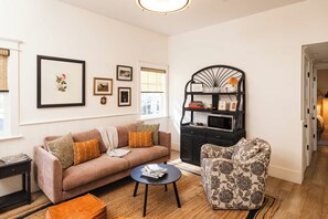 A living room with a sofa, armchair, coffee table, and a black bookshelf. - Downtown 3bd Retreat, Newly Updated & Bright! (Charleston)
