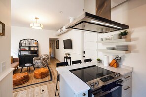 A modern kitchen with a built-in stove, a dining area with a table and chairs, and a living room with a sofa and a coffee table. - Downtown 3bd Retreat, Newly Updated & Bright! (Charleston)