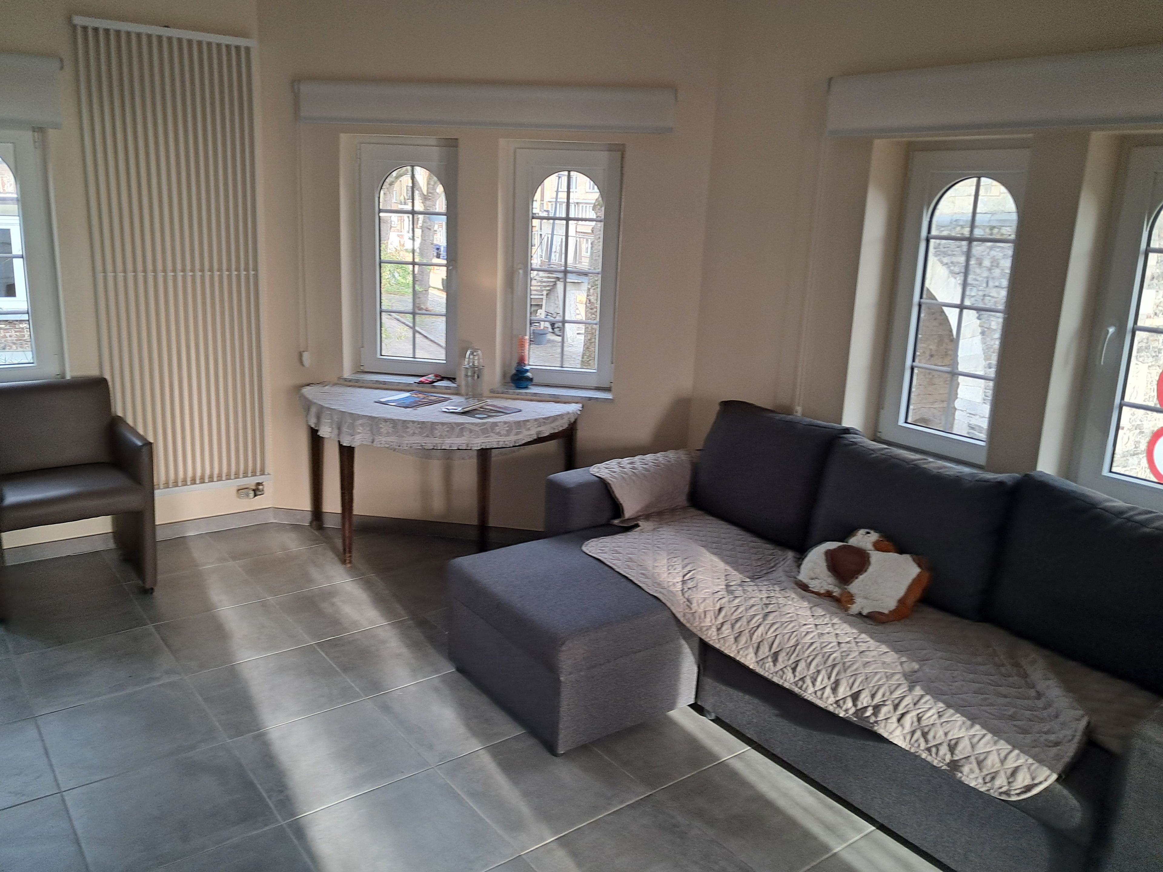 Una sala de estar con un sofá gris, una mesita redonda y dos ventanas con arcos.
