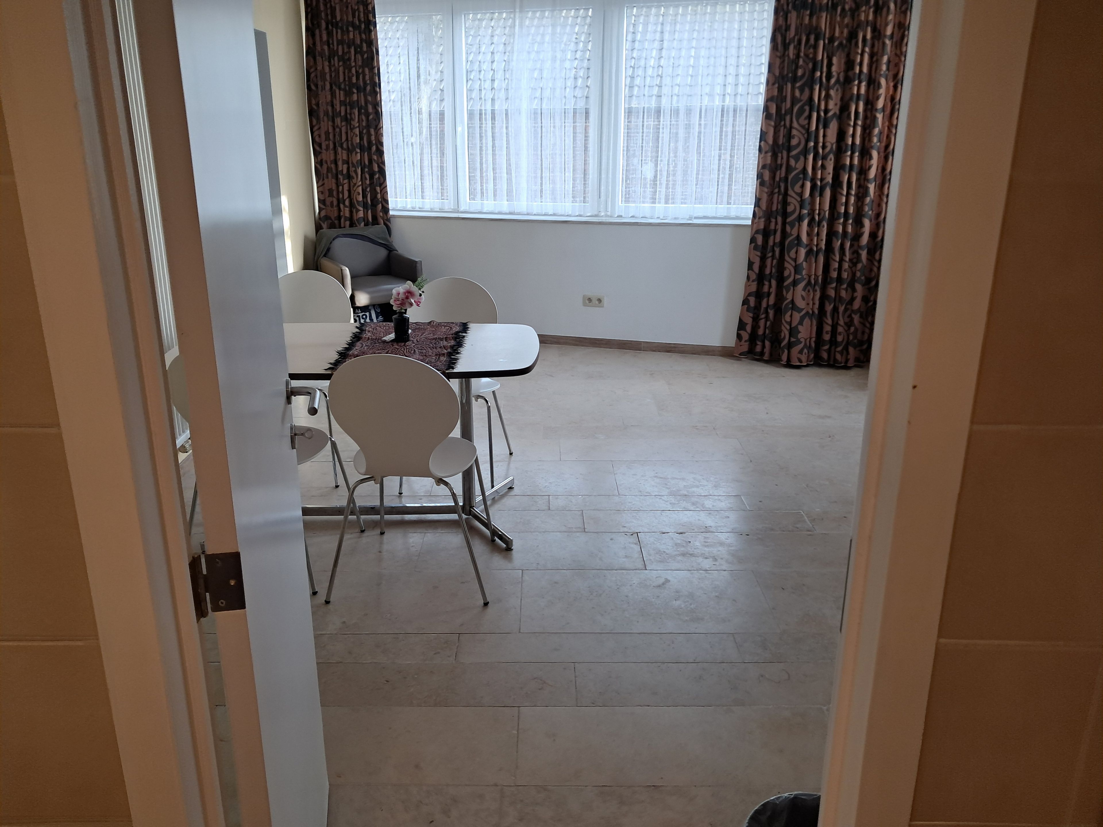 A dining area with a table, chairs, and a window with curtains.