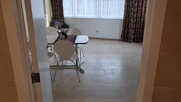 A dining area with a table, chairs, and a window with curtains.