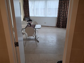 Un comedor con una mesa, sillas y un ventanal con cortinas.