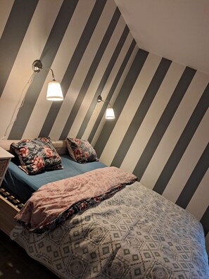 Een kamer met een bed, twee wandlampen en gestreepte wanden.
