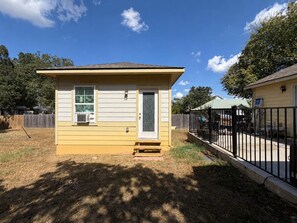 A small single-story house with a front door, a window, and a small porch. - The Cozy Cardinal Studio (Bastrop)