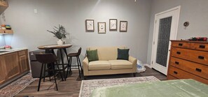 A compact living space with a kitchenette, a dining area, a sofa, and a bed. - The Cozy Cardinal Studio (Bastrop)