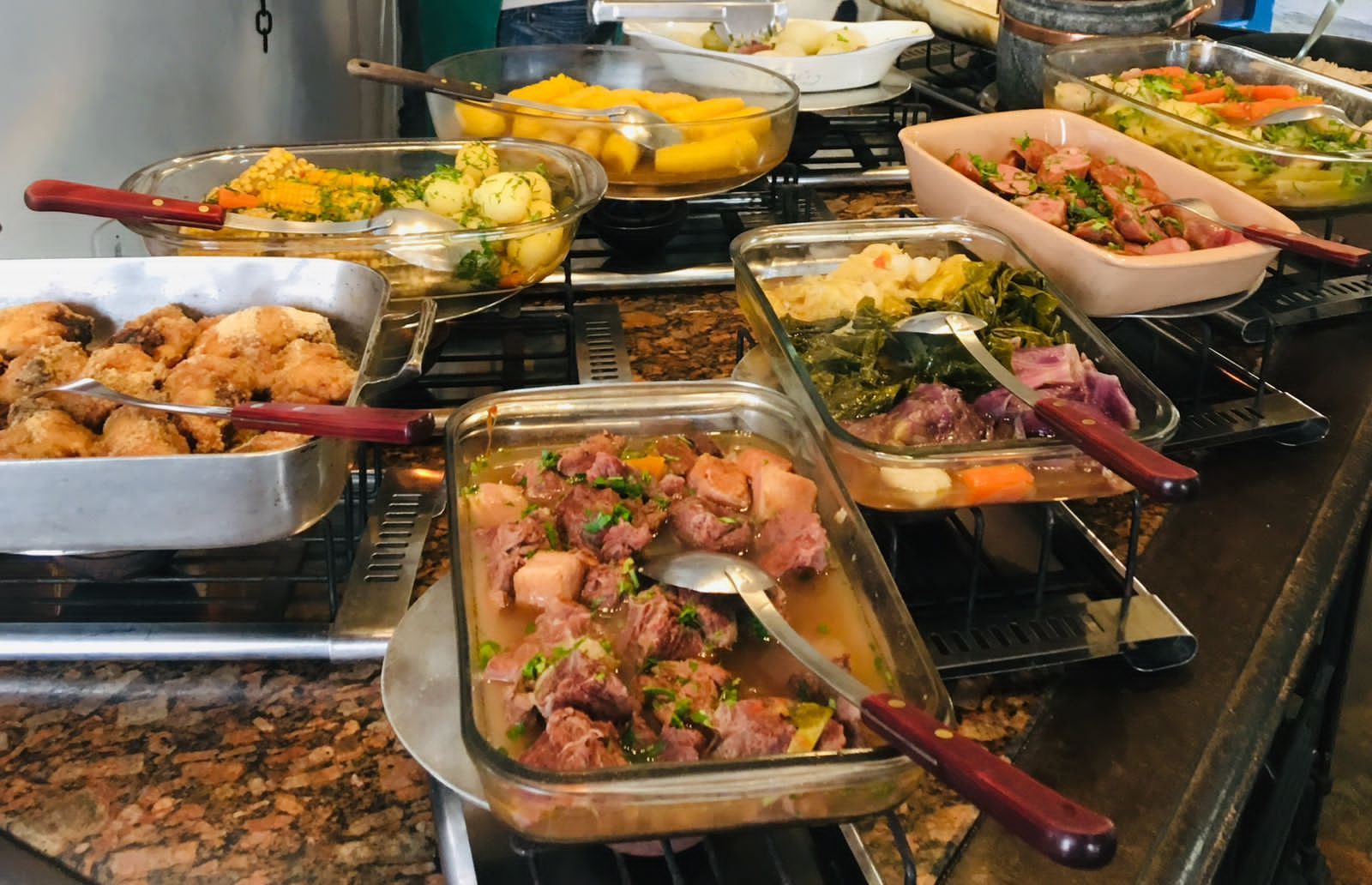 A buffet with various dishes including meats, vegetables, and salads.