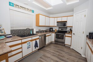 Una cocina moderna con armarios blancos, lavavajillas de acero inoxidable y horno empotrado.