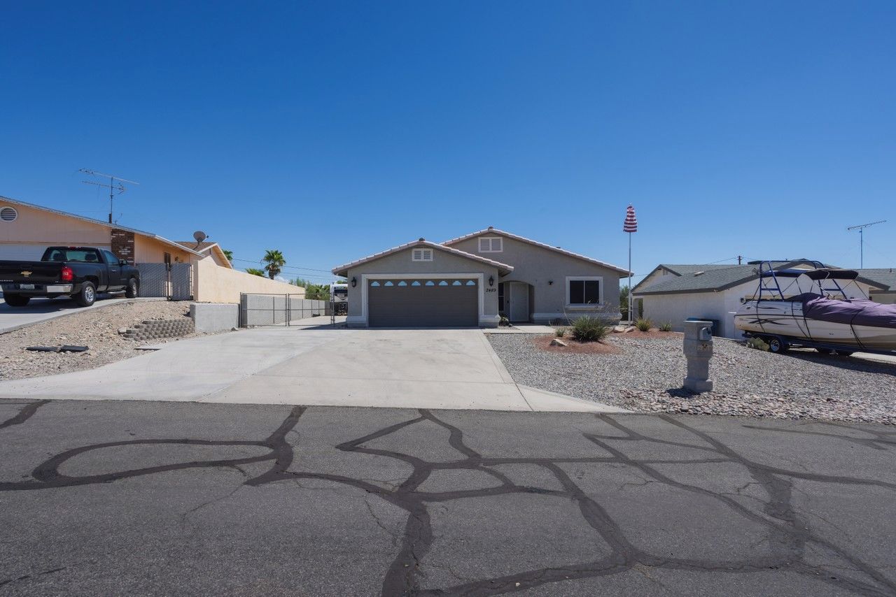 A residential driveway with a garage, a parked truck, and a boat trailer.