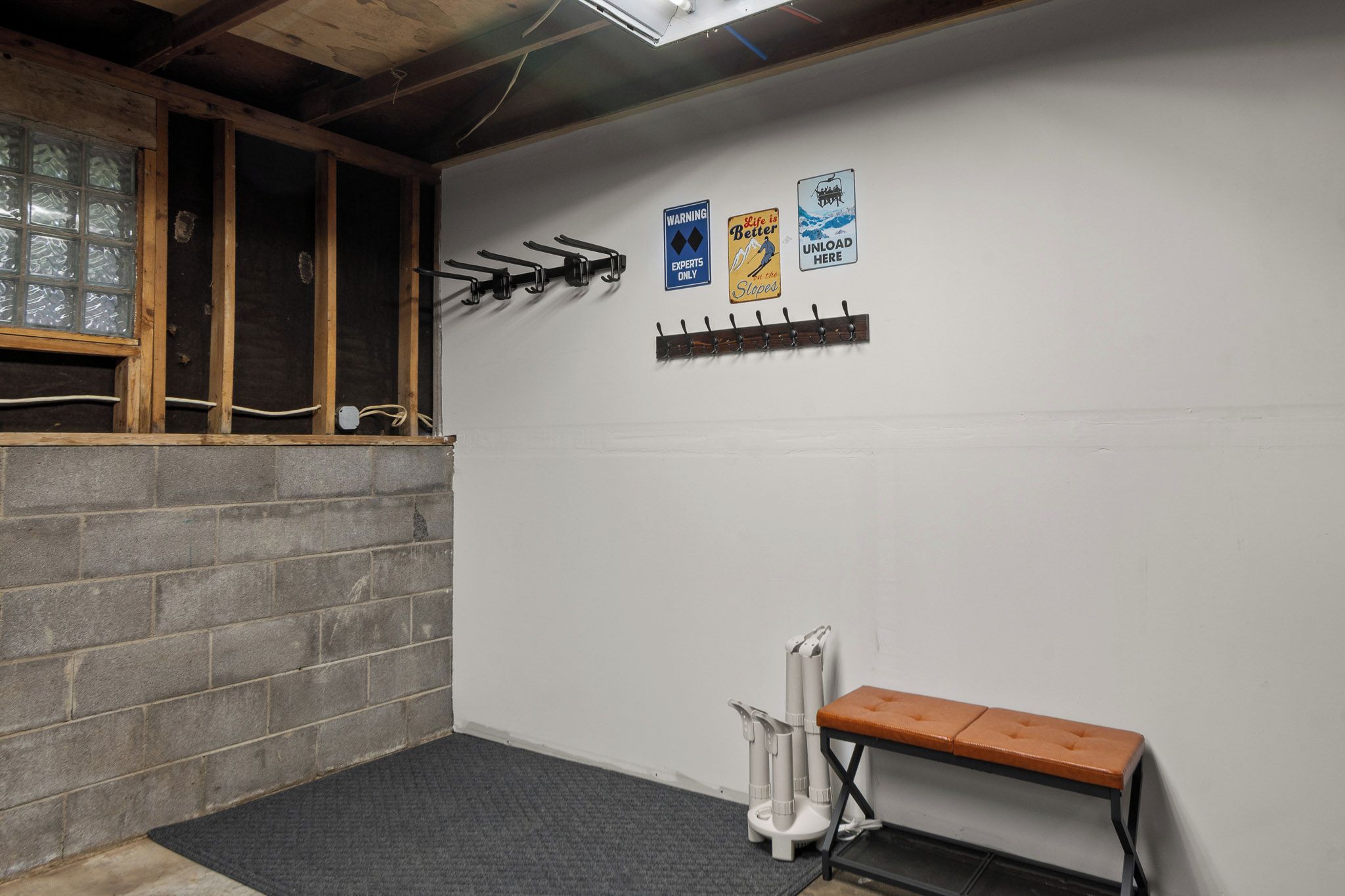Une pièce avec un banc, un radiateur et des crochets fixés au mur.