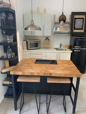 Eine moderne Küche mit einem Holztisch, schwarzen Stühlen, einem eingebauten Ofen und einem schwarzen Kühlschrank.
