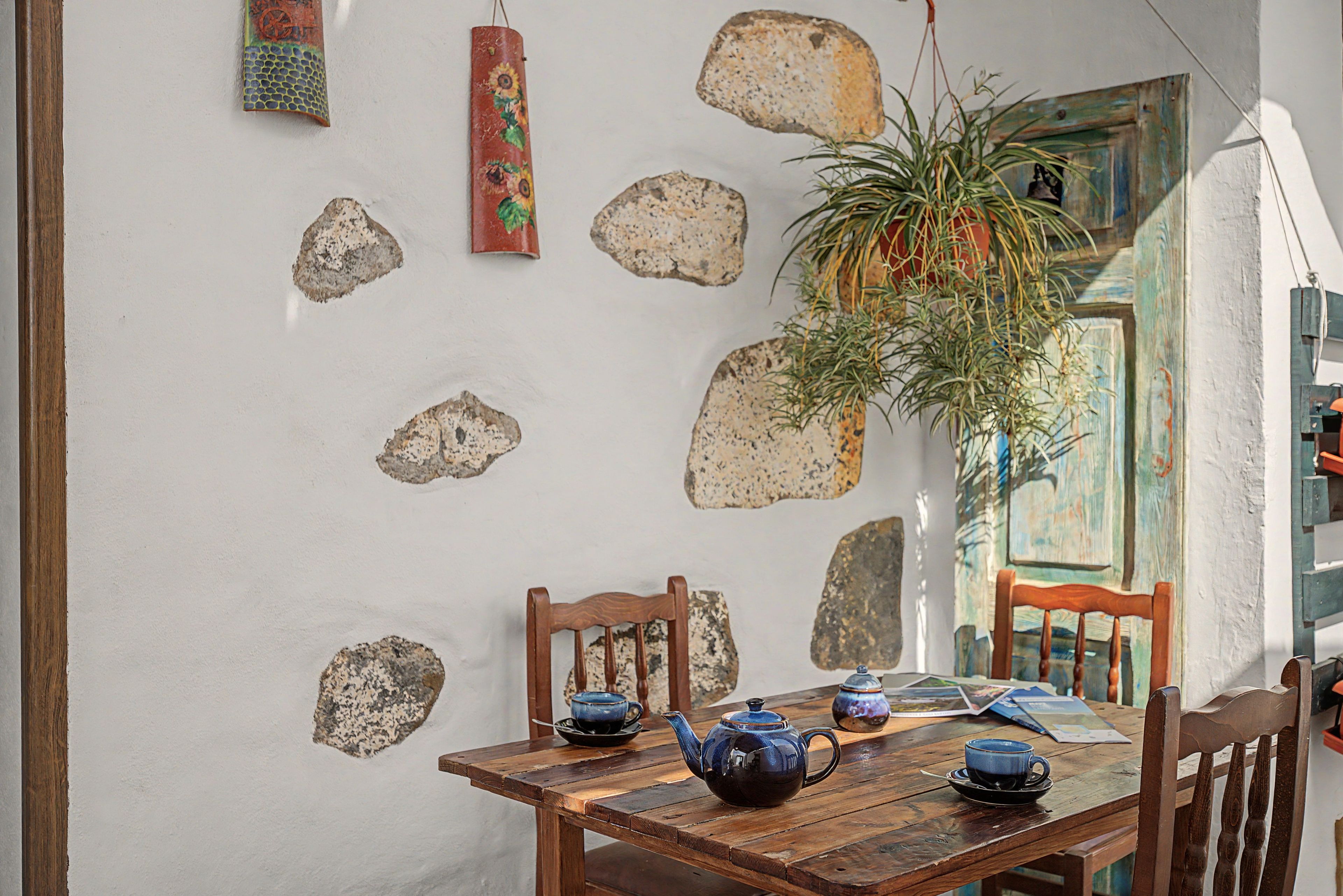 Un comedor rústico con una mesa de madera, sillas y una planta colgante.