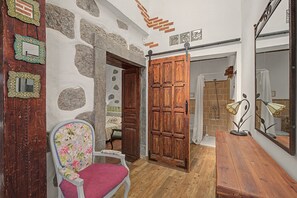 Una habitación con una puerta de madera, una silla estampada con motivos florales y una mesa de madera.
