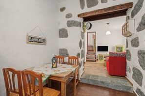 A dining area with a table and chairs, a staircase leading to a living room with a red sofa, and a 'BIENVENIDOS' sign on the wall. - Vacation Home 'Gloria' with Mountain Views, Shared Terrace & Wi-Fi (Arucas)