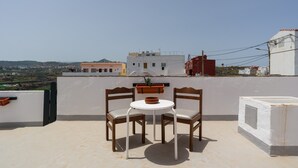 A rooftop terrace with two wooden chairs, a small table, and a potted plant. - Vacation Home 'Gloria' with Mountain Views, Shared Terrace & Wi-Fi (Arucas)