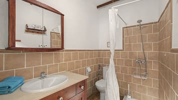 Une salle de bain avec un meuble-lavabo en bois, un évier, des toilettes et un espace douche.