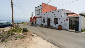 A two-story building with a red roof and white walls, a garage, and potted plants. - Vacation Home 'Gloria' with Mountain Views, Shared Terrace & Wi-Fi (Arucas)