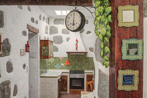 Una cocina con pared de piedra, un reloj colgante y un revoque de azulejos.