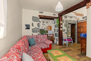 A cozy living room with a patterned sofa, a wooden coffee table, and a stone wall.