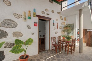 Un espace extérieur aménagé dans un style rustique, avec des murs en pierre, des meubles en bois et des plantes en pot.