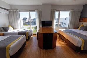 A hotel room with two beds, a TV, and a balcony with a city view. - Aura Hotel Recoleta (Buenos Aires)