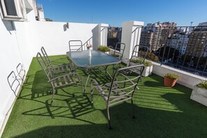 A rooftop terrace with a glass table and metal chairs, surrounded by artificial grass and potted plants. - Aura Hotel Recoleta (Buenos Aires)