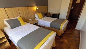 A hotel room with two beds, wooden headboards, a bedside table with a phone, and a small desk with a chair. - AURA HOTEL RECOLETA (Buenos Aires)