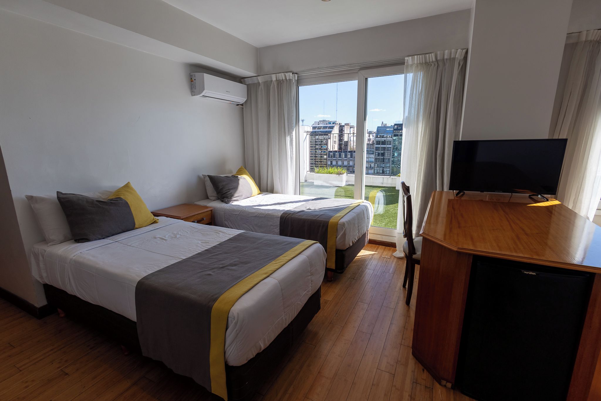 Habitació d'hotel amb dos llits, televisió i vista a la ciutat.