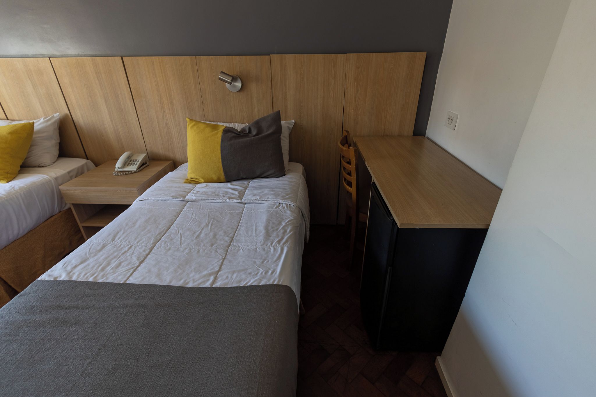 Habitación de hotel con dos camas, un escritorio, una silla y un teléfono.
