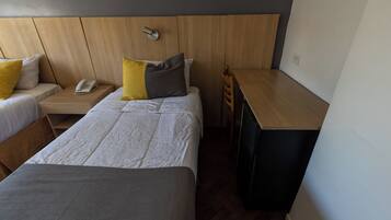 Habitación de hotel con dos camas, un escritorio, una silla y un teléfono.