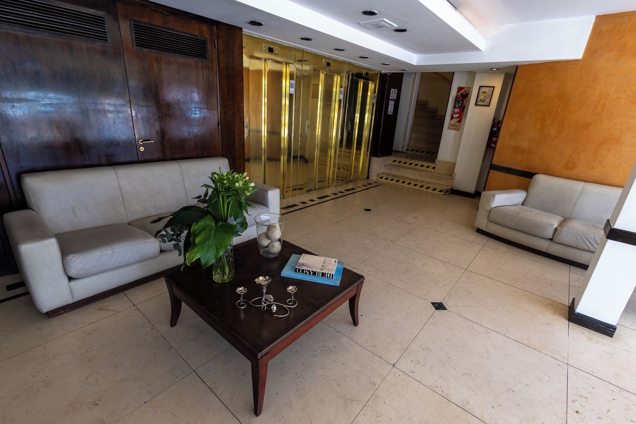 Un hall con dos sofás, una mesa de centro con adornos y una escalera que lleva a un ascensor.