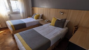 A hotel room with two beds, a wooden headboard, a bedside table with a phone, and a window with curtains. - AURA HOTEL RECOLETA (Buenos Aires)
