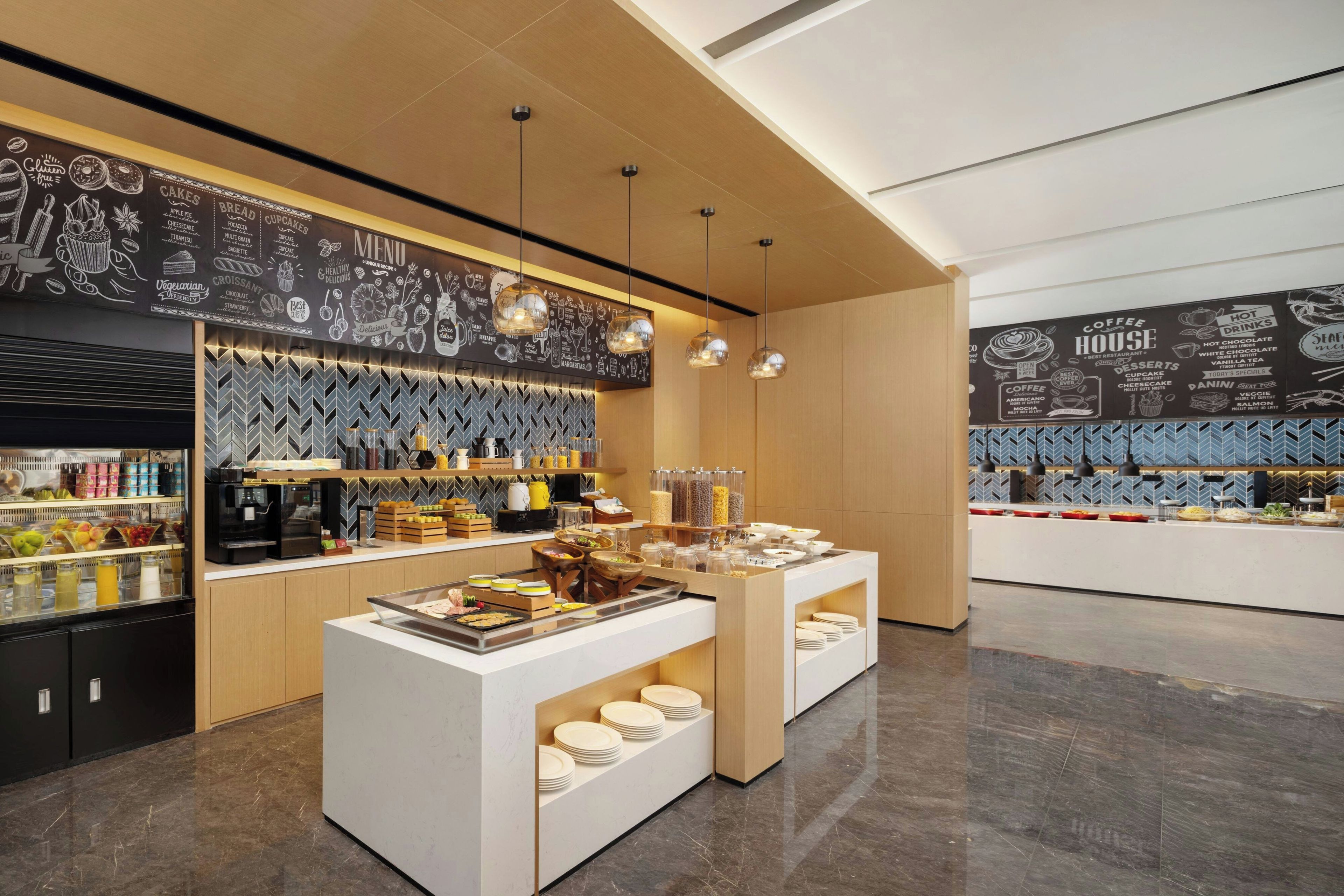 A modern cafe interior with a chalkboard menu, coffee station, and food display.