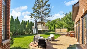 A backyard with a patio area, outdoor furniture, a barbecue grill, and a wooden deck. - Luxe 4-bedroom house with pool in charming Skokie (Skokie)