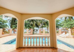 A covered outdoor area with a pool, palm trees, and a view of a beach. - Wiona of Villa Paraiso | Beachfront Villa & Pool (Bocas del Toro Province)