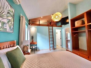 Ein Schlafzimmer mit einem Bett, einem Schreibtisch, einem Stuhl, einer Leiter und einem Kleiderschrank.