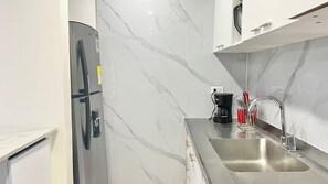 A modern kitchen with a stainless steel refrigerator, a coffee maker, and a sink with a faucet. - Moon House: Modern, Comfortable, and Elegant. (Cali)