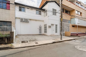A residential building with a gated entrance, a visible garage door, and a street in front. - Moon House: Modern, Comfortable, and Elegant. (Cali)